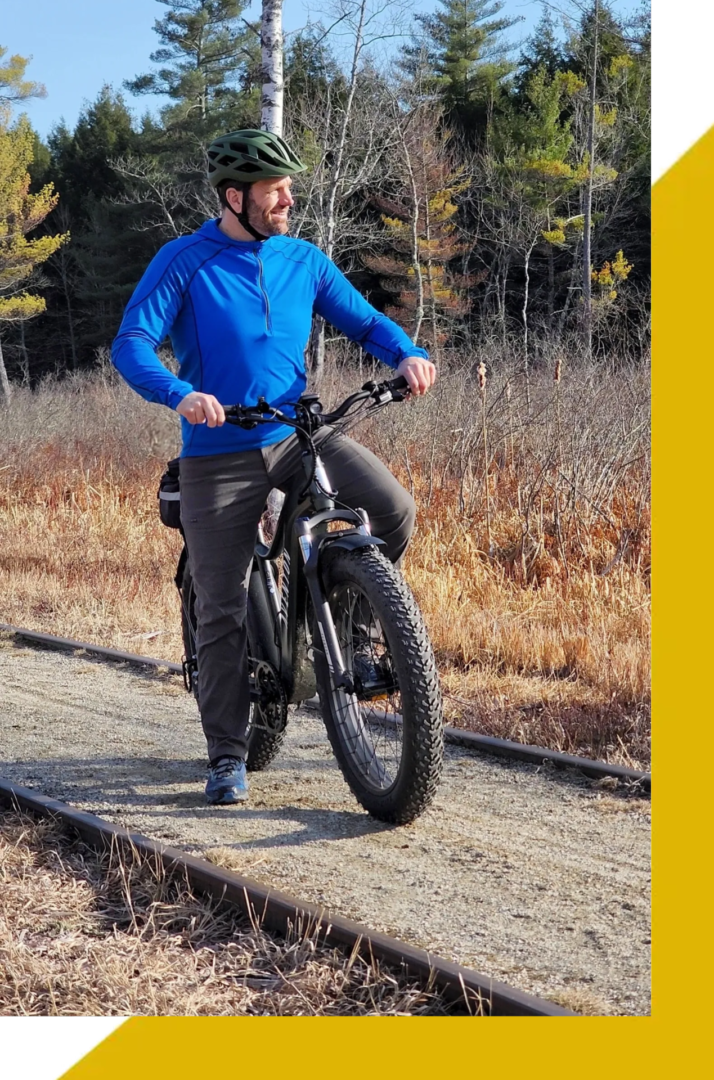 A man in blue shirt riding a bike on dirt road.