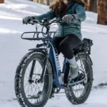 A woman riding on the back of a bicycle in snow.