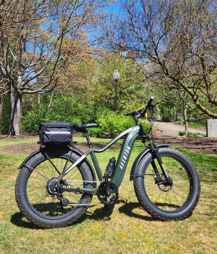 A bicycle parked in the grass near some trees.