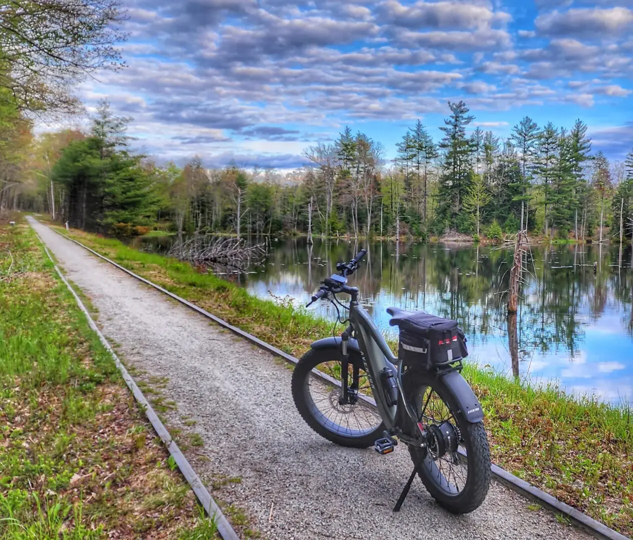 A bicycle parked on the side of a road near water.